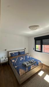 a bedroom with a bed with a blue comforter and a window at Eirene Residence in Vrnjačka Banja +10 photos
