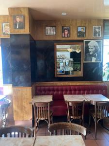 a restaurant with wooden tables and a red couch at Hôtel Au Bon coin chez Pierre in Franconville +10 photos