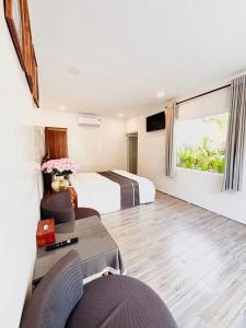 a hotel room with two beds and a table and chairs at Hoang Phuc resort in Rạch Giá