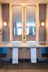 a bathroom with two sinks and two mirrors at Barceló Tenerife Royal Level in San Miguel de Abona