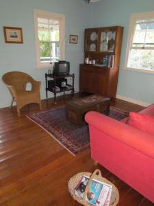 a living room with a red couch and a table at Whitsunday Cane Cutters Cottage in Cannon Valley