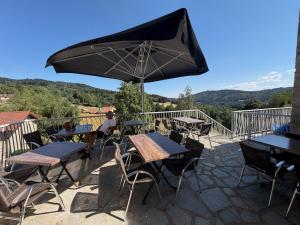 a patio with tables and chairs and an umbrella at L'Eden du Forez in Le Brugeron