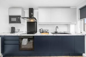a kitchen with blue and white cabinets and a sink at 3-Bed Home in East Kilbride Ideal for Contractors & Longer Stays from Voyage Collection in East Kilbride
