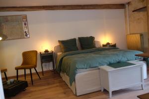 a bedroom with a bed and two tables and a chair at Ferme La Hougue B&B in Coigny