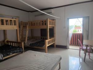 a room with bunk beds and a table and a window at FUBON World Guesthouse in Ban Nongpapao