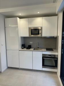 a kitchen with white cabinets and a sink and a microwave at Studio du Lac in Créteil +7 photos