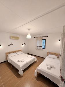 two beds in a room with white walls at Petrinos Butik Otel in Datca +5 photos