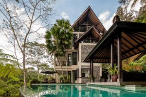 a house with a swimming pool in front of a house at Villa Naga Putih in Ubud