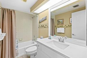a bathroom with a sink and a toilet and a tub at Gorgeous and well appointed efficiency with shared pool and beach access in Destin