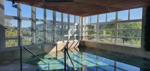 a room with a pool and windows with a view at L'Eden du Forez in Le Brugeron