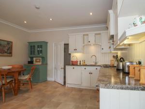 a kitchen with green and white cabinets and a table at The Old Nursery in Much Wenlock