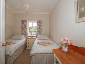 a bedroom with two beds and a table and a window at The Old Nursery in Much Wenlock