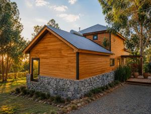 a wooden house with a stone wall at Cabañas Valle de los Ciervos in Tandil