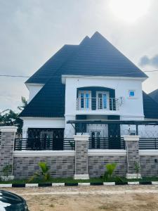 a white house with a black roof at DAS Apartments Lugbe in Abuja