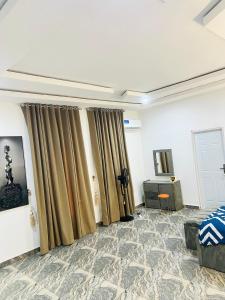 a room with curtains and a bed and a table at DAS Apartments Lugbe in Abuja