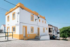 a white house with orange trim on a street at Solar da Fé in Atalaia