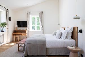 a white bedroom with a bed and a desk at Domaine de Fontenille - Fontenille Collection in Lauris