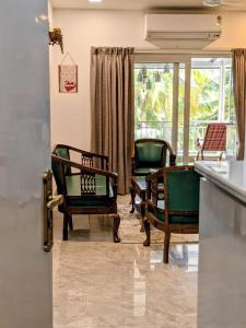 a living room with green chairs and a window at The Palm Retreat Luxe 1bhk Near Thivim Station in Advolpale