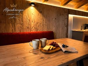 a wooden table with a plate of cheese and two cups at Ferienlodge Alpenkönigin Vacation in Stubai Valley in Neustift im Stubaital