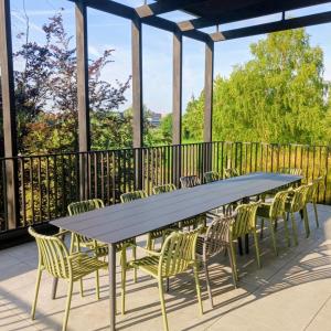 a large table and chairs on a balcony with a view at Het Kasterhuis - Groepsverblijf in Wetteren
