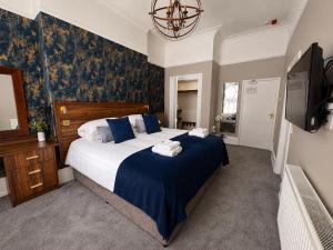 a bedroom with a bed with blue sheets and a tv at Hedley House Hotel Wellness and Spa in York