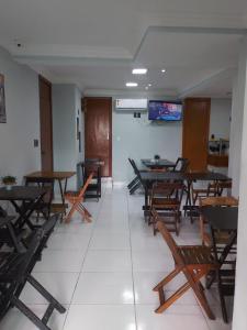a dining room with tables and chairs and a tv at Hotel Luar de Itapua in Salvador