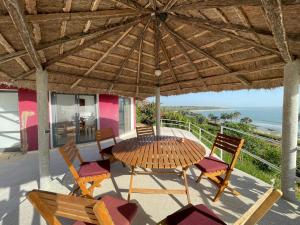 a wooden table and chairs under a wooden umbrella at Les Cases Rouges in Kaolack