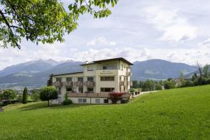 a building on a hill with mountains in the background at B&B Garni Schorneck in Brunico +36 photos