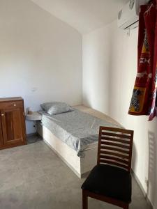 a small bedroom with a bed and a chair at Les Cases Rouges in Kaolack