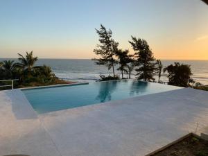 a swimming pool with the ocean in the background at Les Cases Rouges in Kaolack