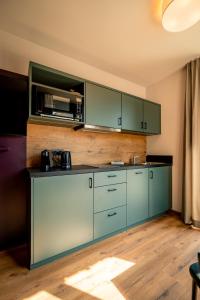 a kitchen with green cabinets and a wooden floor at Adler Apartments in Bach