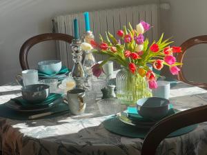 a table with plates and a vase of flowers on it at Ferme La Hougue B&B in Coigny