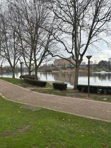 a path next to a river with trees and a body of water at Studio du Lac in Créteil