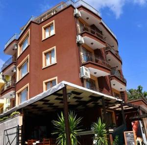 a tall red brick building with palm trees in front of it at Angel in Primorsko