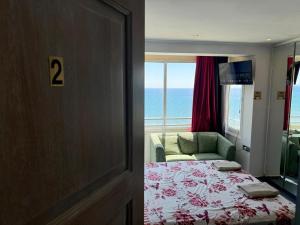 a bedroom with a bed and a couch and a window at Larnaca Seaview Rooms in Larnaca