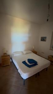 a bedroom with a white bed with a blue towel on it at Residenze Poseidon in Le Castella
