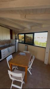 a kitchen with a wooden table and white chairs at Residenze Poseidon in Le Castella