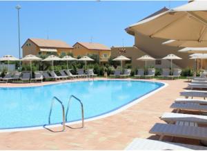 a large swimming pool with chairs and umbrellas at Residenze Poseidon in Le Castella +22 photos