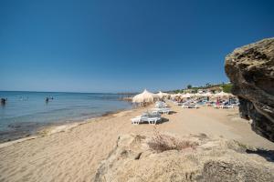 a beach with chairs and umbrellas and people in the water at Residenze Poseidon in Le Castella