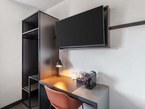 a desk with a lamp and a chair in a room at B&B Hotel Freiburg-Süd in Freiburg im Breisgau