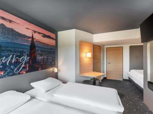 a hotel room with two beds and a desk at B&B Hotel Freiburg-Süd in Freiburg im Breisgau