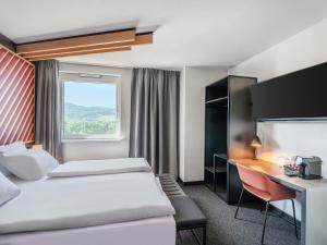 a hotel room with two beds and a desk at B&B Hotel Freiburg-Süd in Freiburg im Breisgau