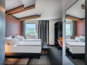 a hotel room with two beds and a tv at B&B Hotel Freiburg-Süd in Freiburg im Breisgau