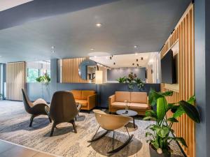 a lobby with a waiting room with chairs and a table at B&B Hotel Freiburg-Süd in Freiburg im Breisgau +21 photos
