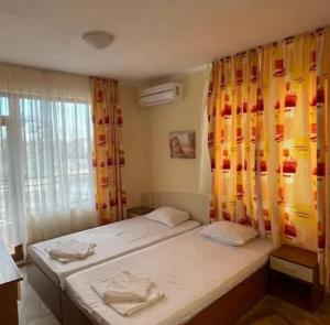 a bedroom with a bed and a window with curtains at Angel in Primorsko