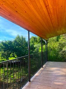 an outdoor deck with a wooden roof and a fence at Cottage Sandro-Sandrooo in Khuts'ubani
