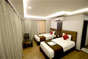 a hotel room with two beds with red pillows at HOTEL RUBY PALACE in Tiruchirappalli +38 photos