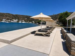 a group of lounge chairs with an umbrella and the water at Studio Anna in Vathi