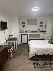a bedroom with a bed and a desk and a kitchen at Guesthouse 1921 in Hartbeespoort