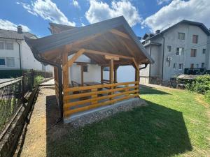 a wooden gazebo in a yard next to a building at Apartmani E&A Jasmina Okanović in Gradačac